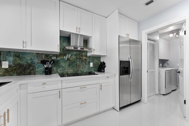 kitchen with white cabinetry, black electric stovetop, independent washer and dryer, stainless steel fridge with ice dispenser, and wall chimney exhaust hood