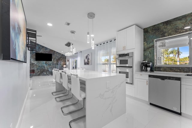 kitchen featuring a kitchen island, light stone countertops, white cabinets, and appliances with stainless steel finishes