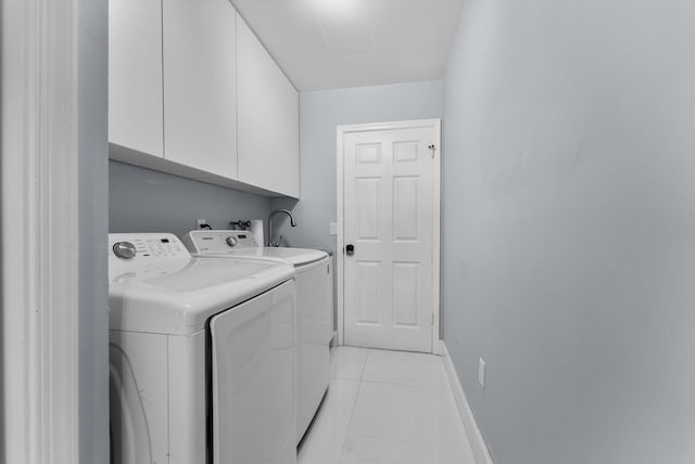 clothes washing area featuring light tile patterned flooring, cabinets, and washer and dryer