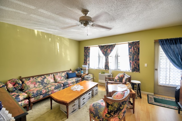 living room featuring a textured ceiling, ceiling fan, and light hardwood / wood-style flooring