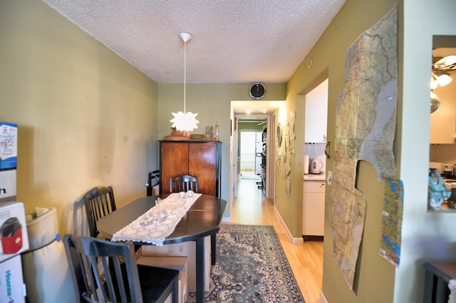 dining space featuring a textured ceiling and light wood-type flooring