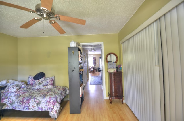 bedroom with ceiling fan, a textured ceiling, and light hardwood / wood-style flooring