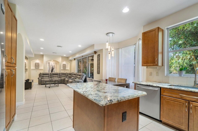 kitchen featuring sink, dishwasher, a kitchen island, pendant lighting, and light stone countertops