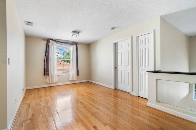 unfurnished living room featuring hardwood / wood-style floors and a textured ceiling