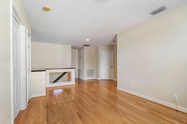 unfurnished living room with a textured ceiling and light wood-type flooring