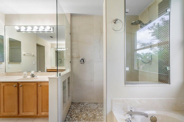 bathroom featuring independent shower and bath, vanity, and a textured ceiling