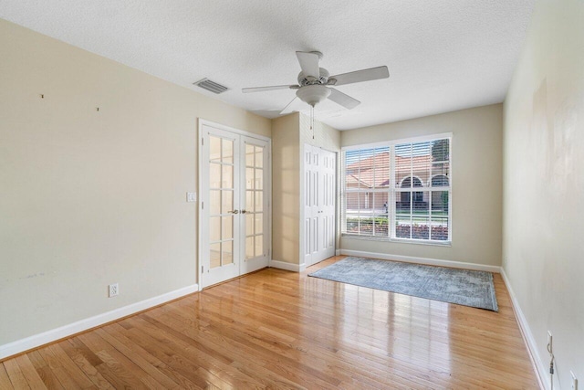 spare room featuring ceiling fan, light hardwood / wood-style flooring, french doors, and a textured ceiling