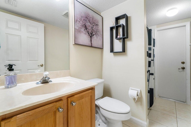 bathroom with vanity, toilet, tile patterned flooring, and a textured ceiling