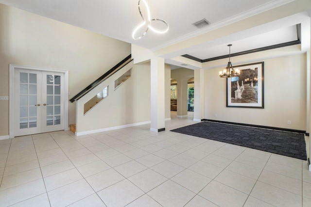 entrance foyer featuring crown molding, a tray ceiling, french doors, and light tile patterned floors