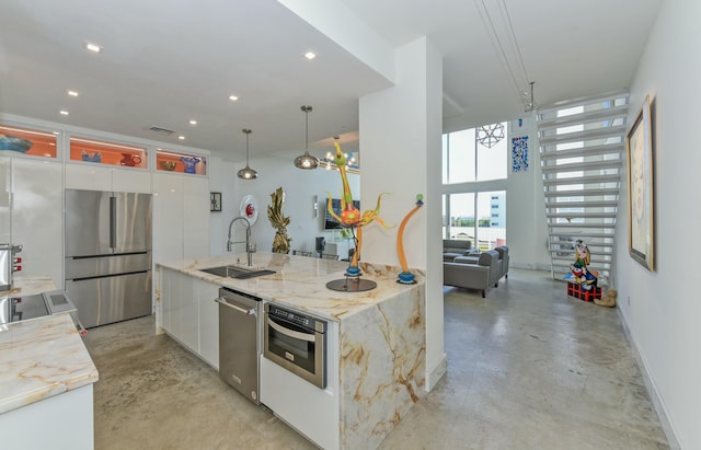 kitchen with sink, appliances with stainless steel finishes, pendant lighting, a large island, and white cabinets