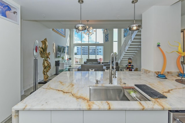 kitchen with light stone counters, decorative light fixtures, and white cabinets