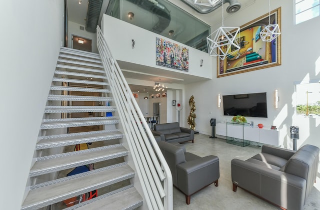 living room featuring an inviting chandelier, a towering ceiling, and concrete flooring