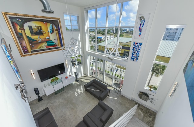 living room with plenty of natural light, concrete floors, and a high ceiling