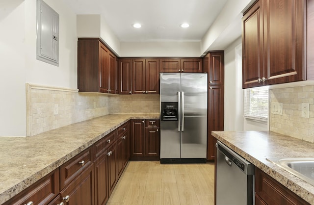 kitchen featuring decorative backsplash, stainless steel appliances, light hardwood / wood-style floors, and electric panel