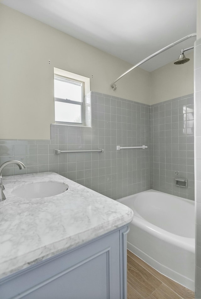 bathroom featuring tiled shower / bath, vanity, wood-type flooring, and tile walls