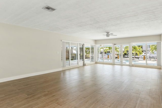 unfurnished room with a textured ceiling, french doors, ceiling fan, and light wood-type flooring