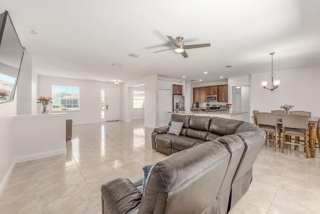 tiled living room featuring ceiling fan with notable chandelier