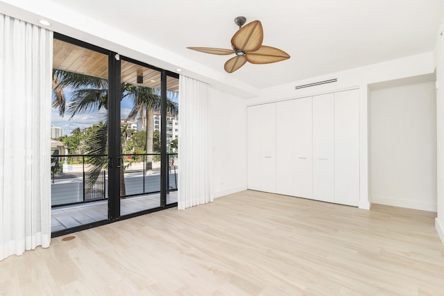 spare room featuring ceiling fan, a wall of windows, and light hardwood / wood-style floors