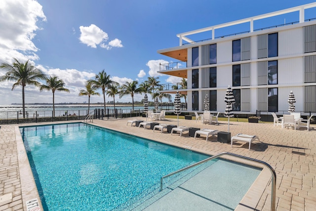 view of pool featuring a water view and a patio area