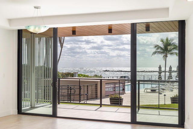 doorway featuring a water view, floor to ceiling windows, and hardwood / wood-style floors