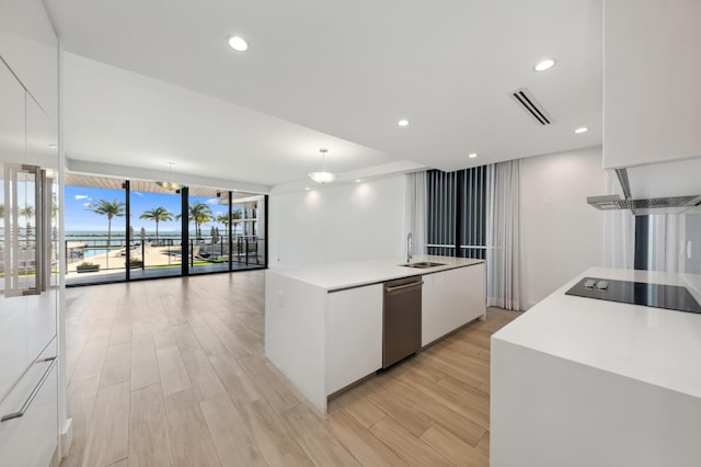 kitchen featuring decorative light fixtures, dishwasher, an island with sink, light hardwood / wood-style floors, and white cabinets