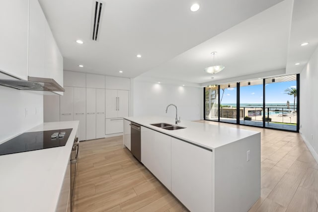 kitchen featuring white cabinetry, sink, a large island with sink, stainless steel dishwasher, and black electric stovetop