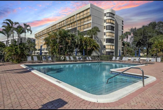 pool at dusk with a patio area