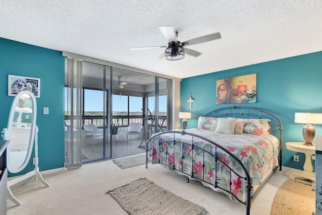 bedroom featuring light colored carpet, a wall of windows, a textured ceiling, access to outside, and ceiling fan