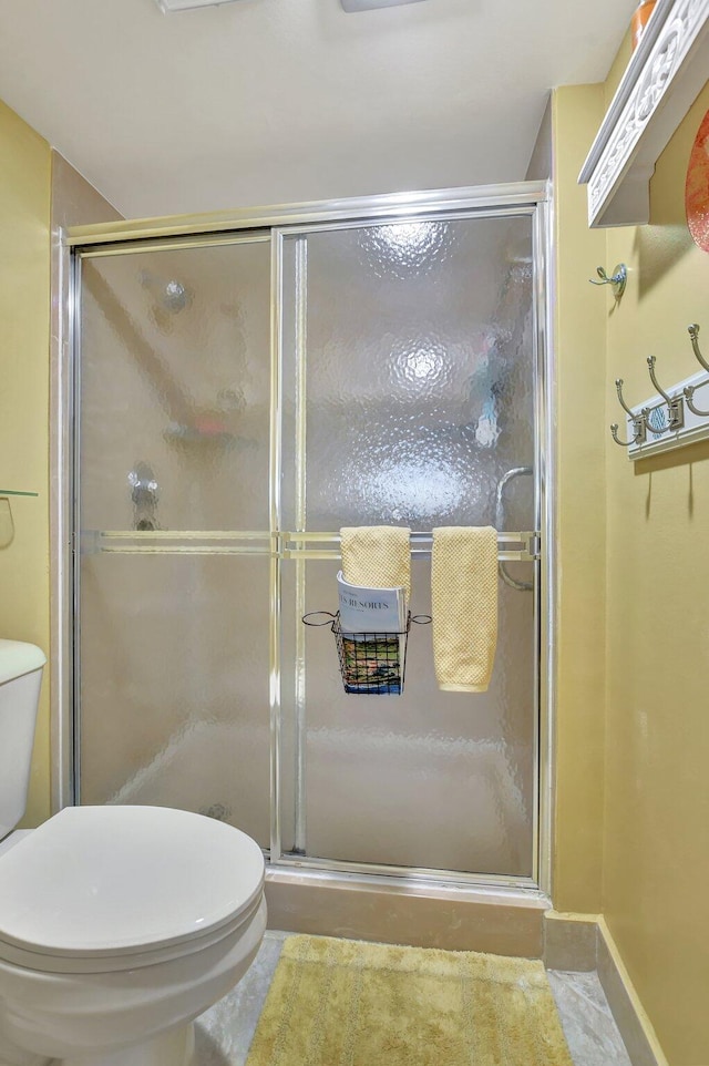 bathroom featuring tile patterned floors, a shower with door, and toilet