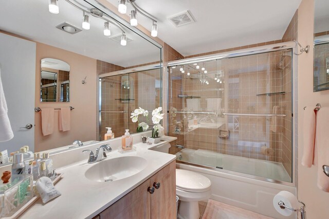 full bathroom with vanity, shower / bath combination with glass door, and toilet