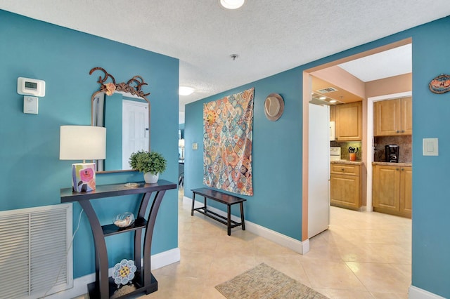 hall with a textured ceiling and light tile patterned floors