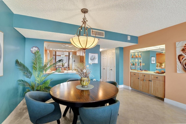 tiled dining room featuring sink and a textured ceiling