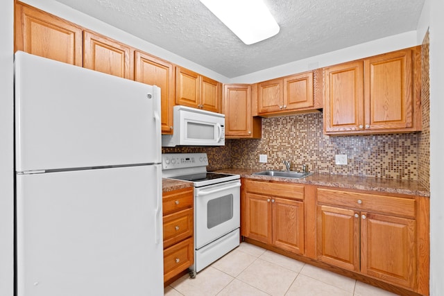 kitchen featuring tasteful backsplash, sink, light tile patterned floors, white appliances, and a textured ceiling