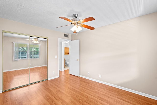 unfurnished bedroom featuring ceiling fan, a textured ceiling, light hardwood / wood-style floors, and a closet