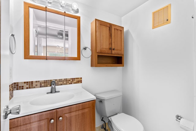 bathroom with vanity, toilet, and decorative backsplash