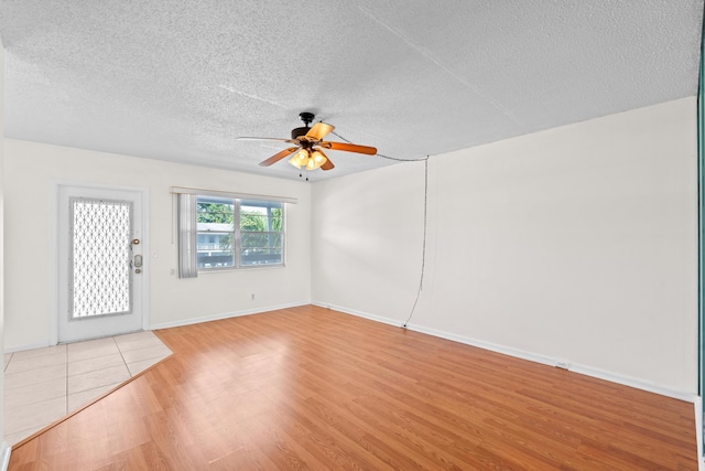 spare room featuring a textured ceiling, ceiling fan, and light wood-type flooring