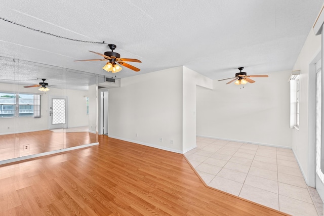 unfurnished living room featuring ceiling fan, light hardwood / wood-style floors, and a textured ceiling