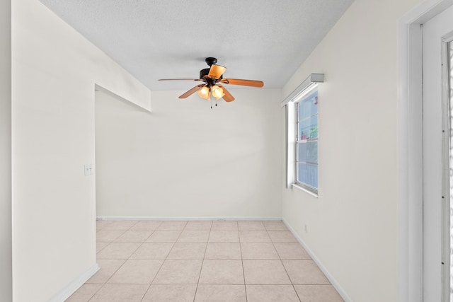 tiled empty room with ceiling fan and a textured ceiling