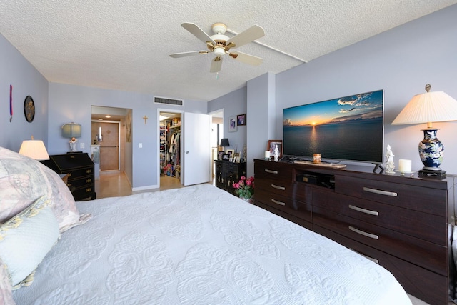 bedroom with ceiling fan, a closet, a spacious closet, and a textured ceiling