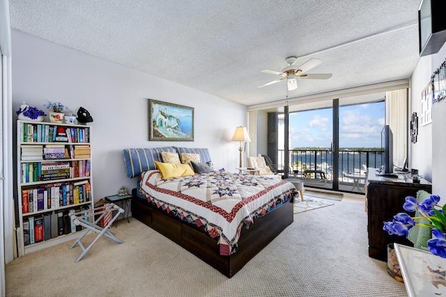 bedroom with ceiling fan, carpet flooring, access to exterior, and a textured ceiling