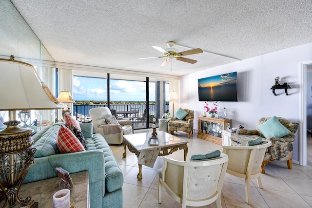 tiled living room with ceiling fan, a wall of windows, and a textured ceiling