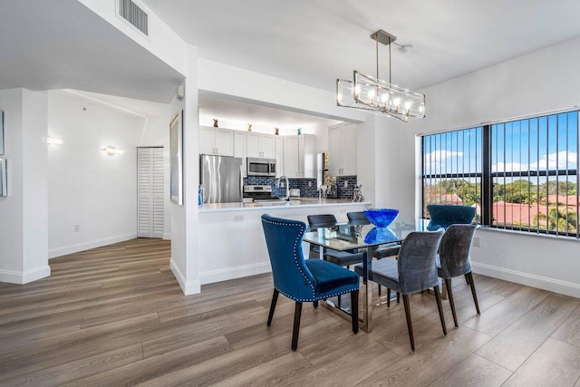 dining space with hardwood / wood-style floors and an inviting chandelier