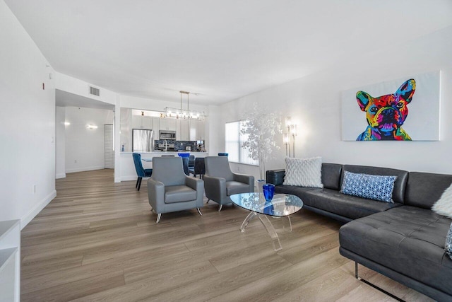 living room with an inviting chandelier and light hardwood / wood-style floors