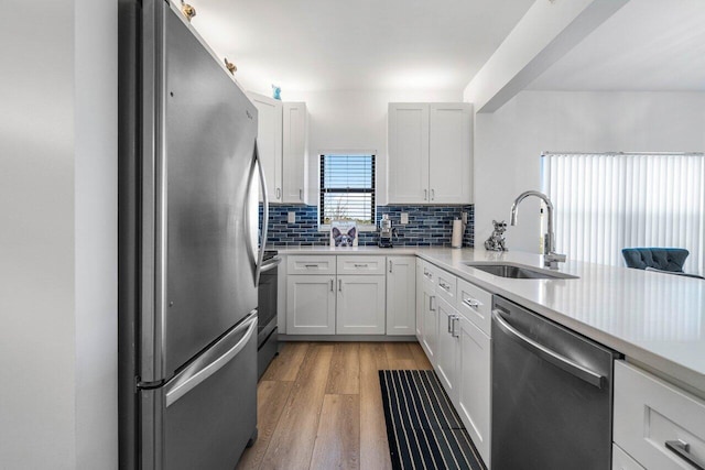 kitchen featuring white cabinetry, sink, stainless steel appliances, and kitchen peninsula