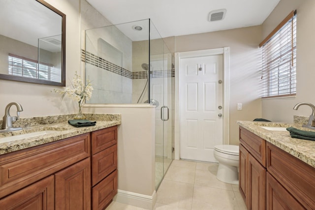 bathroom with a shower stall, toilet, vanity, and tile patterned floors