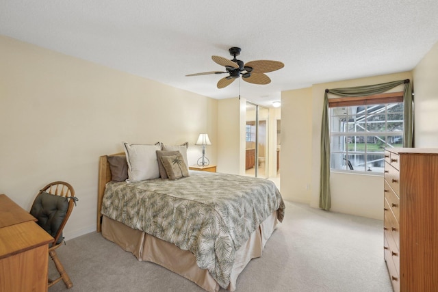 bedroom with ceiling fan, ensuite bathroom, and light colored carpet