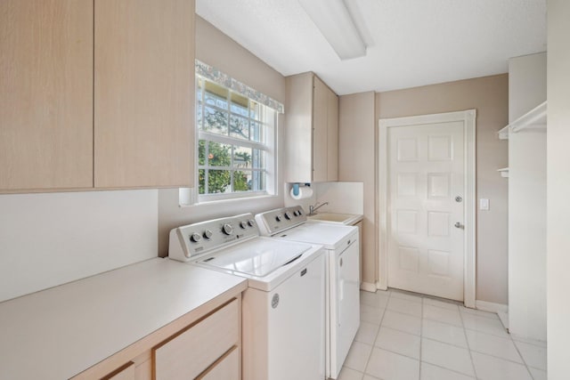 clothes washing area featuring a sink, washer and clothes dryer, light tile patterned floors, cabinet space, and baseboards