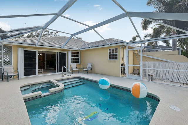 view of pool featuring a patio area, glass enclosure, and a pool with connected hot tub