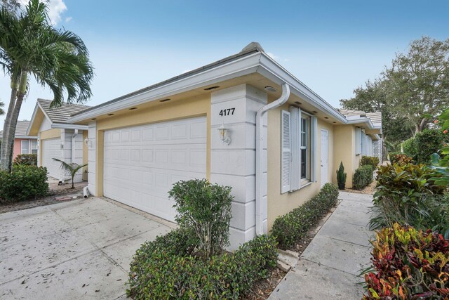 view of side of property featuring concrete driveway and stucco siding