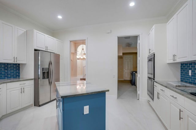 kitchen with ornamental molding, appliances with stainless steel finishes, a kitchen island, and white cabinets